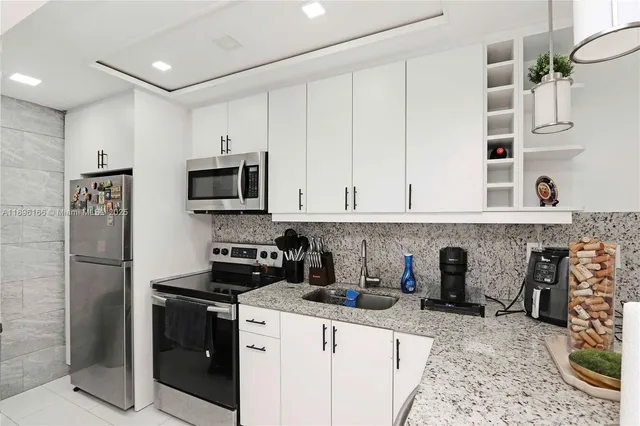a kitchen with stainless steel appliances granite countertop a refrigerator a stove and a sink