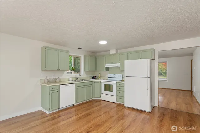 a kitchen with a sink a refrigerator and white cabinets