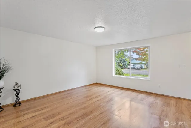 an empty room with wooden floor and window