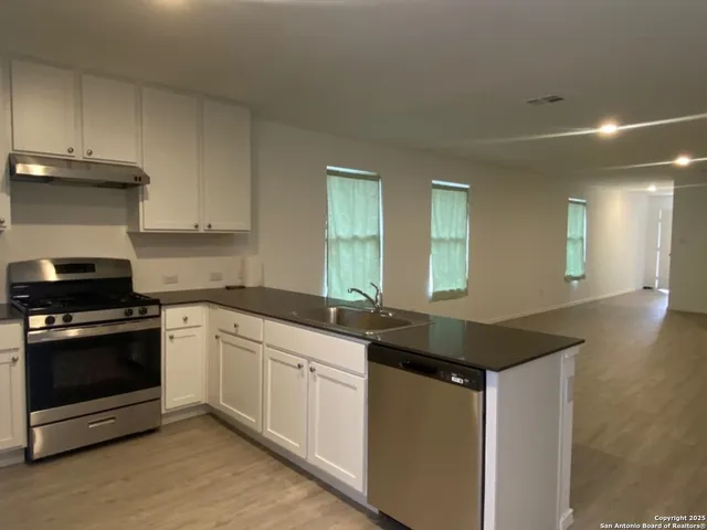 a kitchen with granite countertop a sink a stove and cabinets