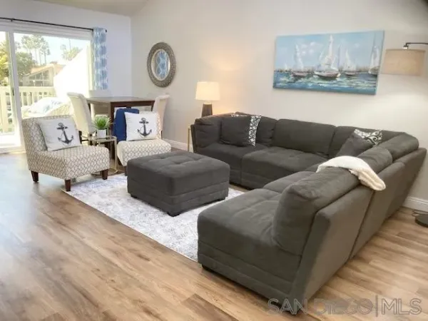 a living room with couches a large mirror on a dresser with wooden floor