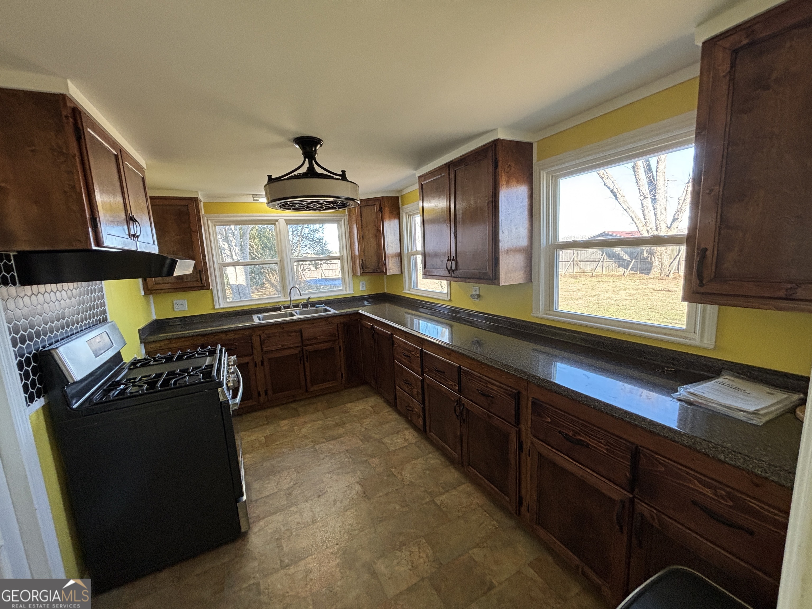 231 Barlow Road Cochran, GA 31014 - Photo 23 of 65 a kitchen with granite countertop wooden cabinets a sink a window and stainless steel appliances