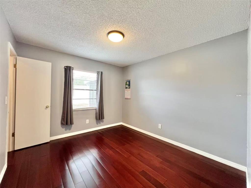 8341 Duval Drive Port Richey, FL 34668 - Photo 17 of 27 an empty room with wooden floor and windows