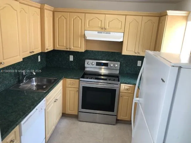 a kitchen with granite countertop a sink stove and cabinets