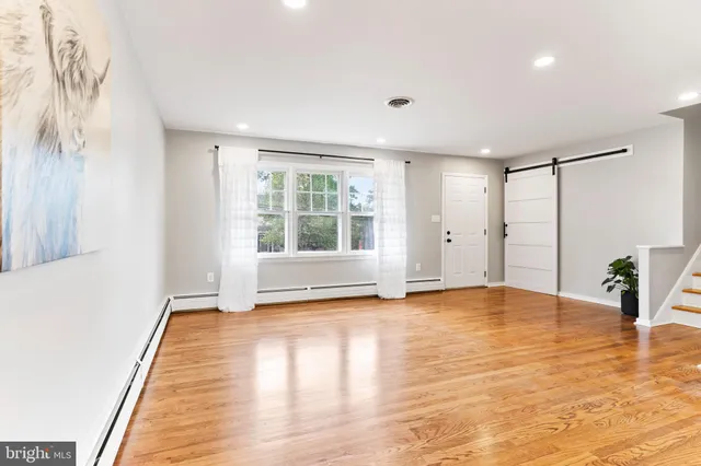 a view of an empty room with window and wooden floor