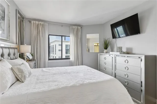 a bedroom with a bed a window and flat screen tv