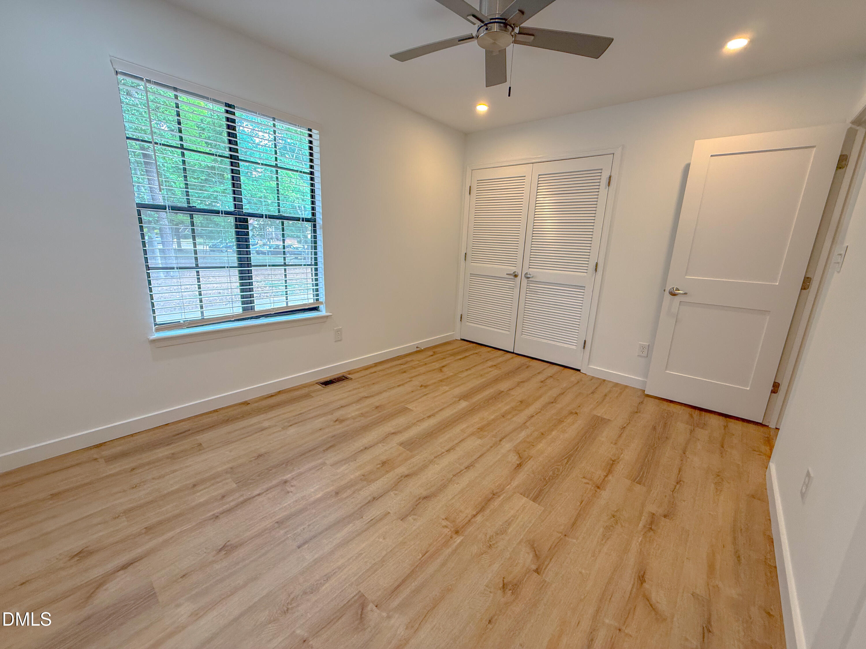4247 The Oaks Drive Raleigh, NC 27606 - Photo 20 of 21 an empty room with wooden floor fan and windows