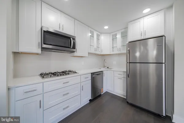a kitchen with stainless steel appliances white cabinets white stove a microwave and a refrigerator