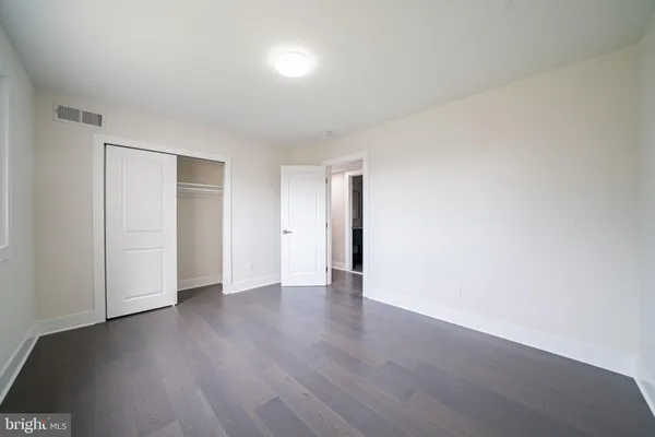 a view of an empty room with wooden floor and closet