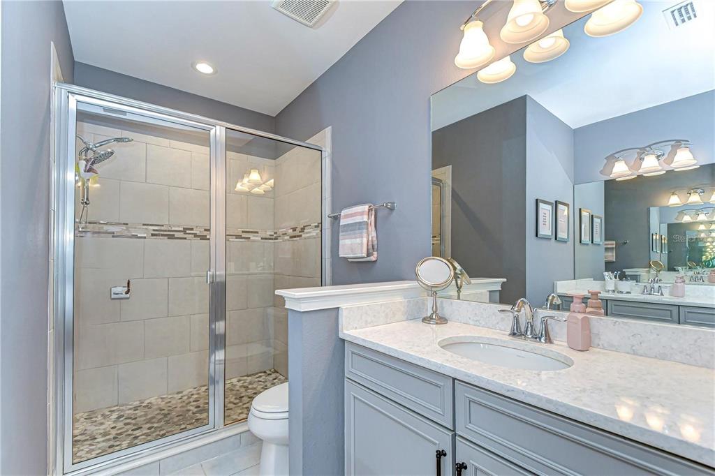 5703 Colony Glen Road Lithia, FL 33547 - Photo 32 of 56 a bathroom with a granite countertop sink a toilet a mirror and shower