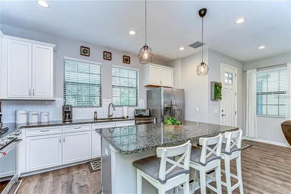 a kitchen with granite countertop a sink a center island stainless steel appliances and cabinets