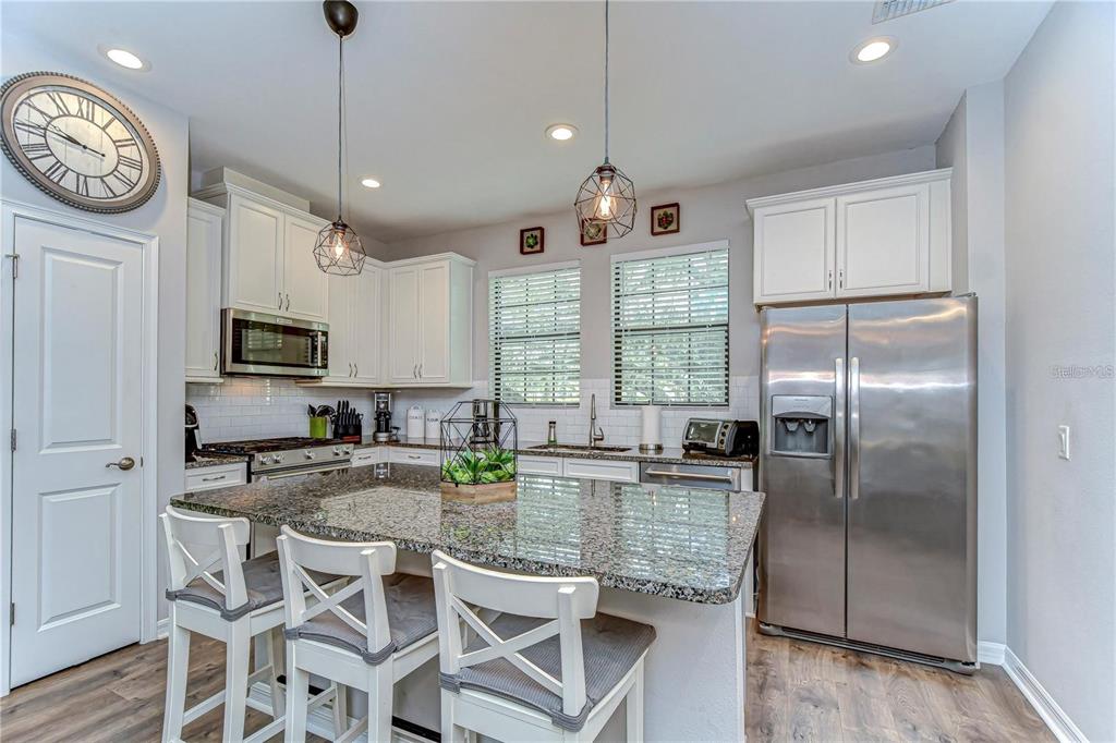 5703 Colony Glen Road Lithia, FL 33547 - Photo 7 of 56 a kitchen with granite countertop a center island a refrigerator a stove a dining table and chairs
