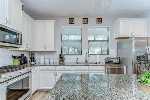a kitchen with granite countertop a refrigerator stove top oven and sink