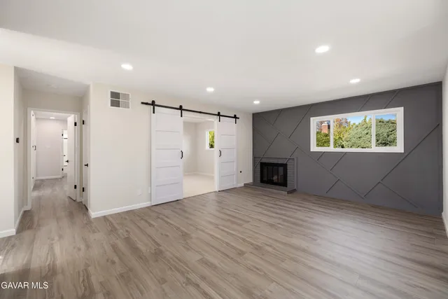 an empty room with wooden floor fireplace and windows