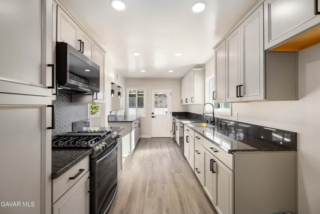 a kitchen with stainless steel appliances granite countertop a stove a sink and a microwave