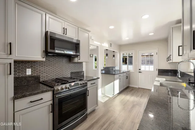 a large kitchen with stainless steel appliances granite countertop a stove a sink and a microwave