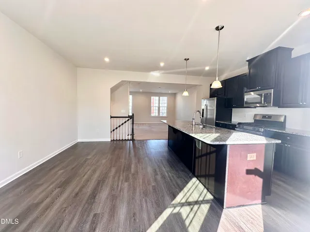 a kitchen with stainless steel appliances granite countertop a sink a stove and a wooden floors