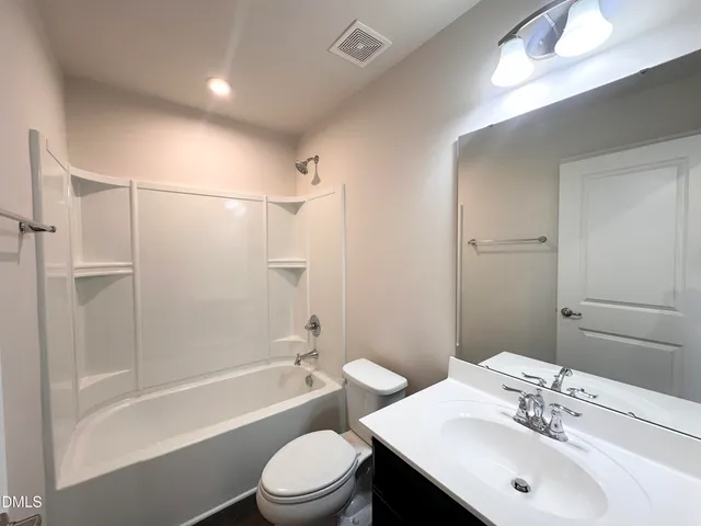 a bathroom with a bathtub shower sink vanity and toilet