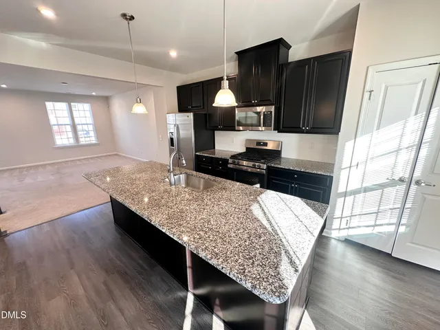 a living room with a table chairs and kitchen view
