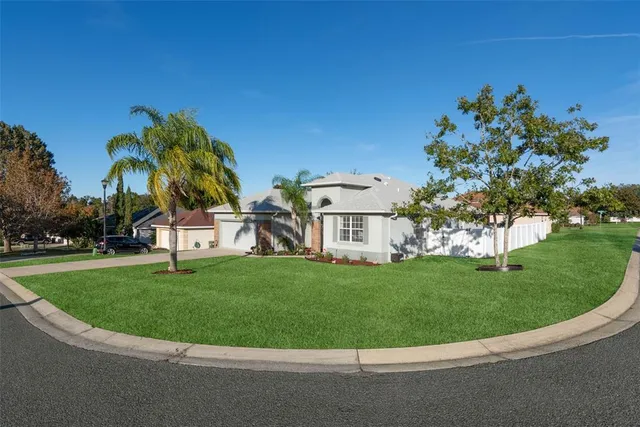 a view of a white house with a big yard and palm trees