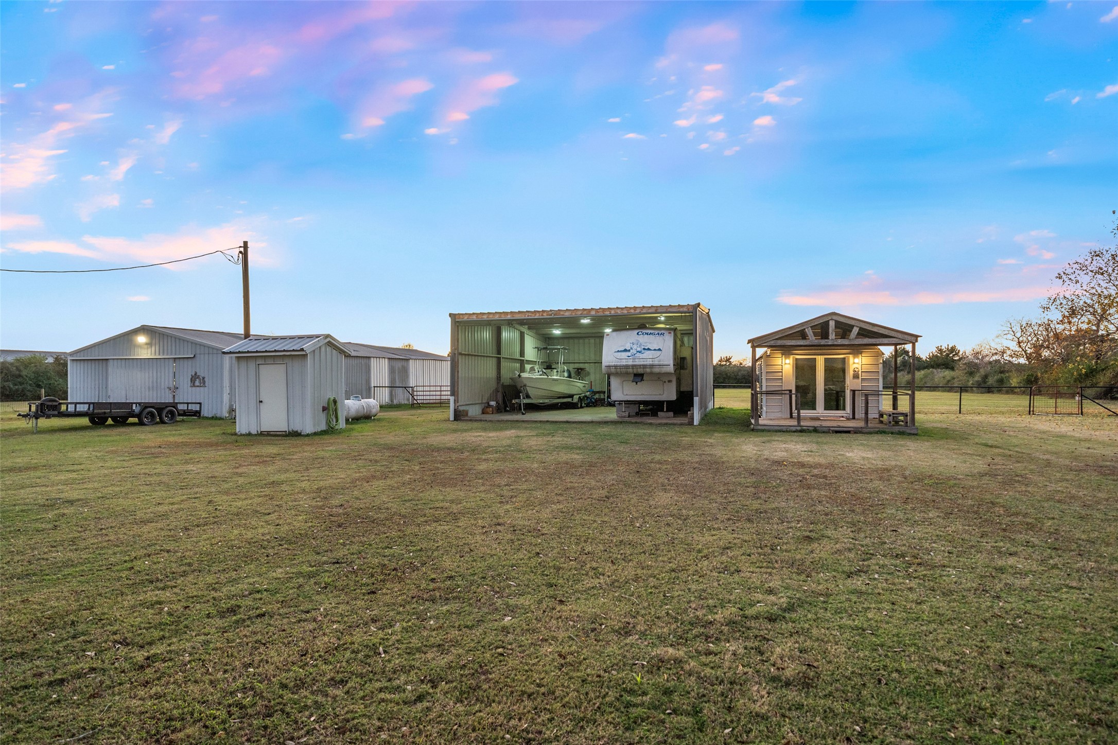 19989 Meadow Bend Road Hempstead, TX 77445 - Photo 5 of 35 Expansive backyard features multiple functional outbuildings, including barn and shop space, supporting a wide range of rural or hobby uses. Portable building to the right is excluded from purchase. Doors can be put on the open barn.