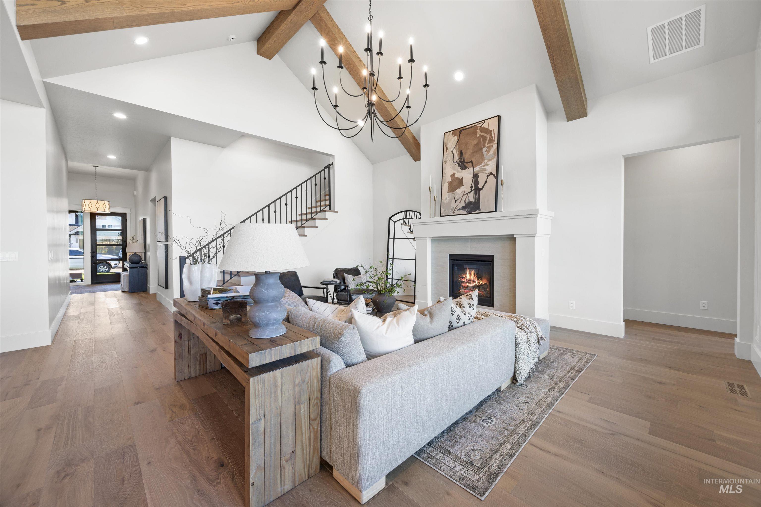 5847 South Pinpoint Way Meridian, ID 83642 - Photo 13 of 44 Living room featuring a chandelier, wood finished floors, and a glass covered fireplace
