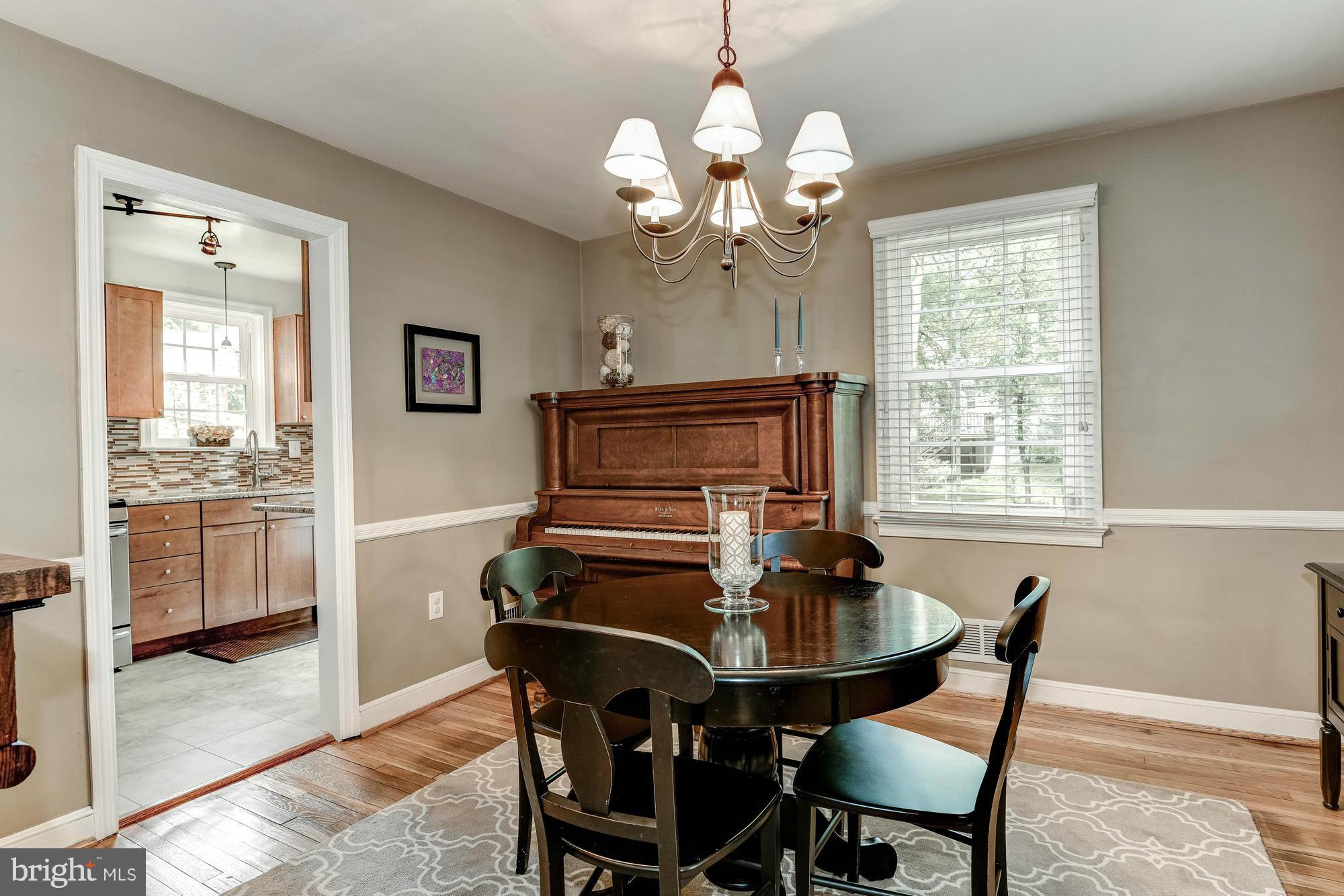 9109 Eton Road Silver Spring, MD 20901 - Photo 5 of 30 a dining room with wooden floor a chandelier a wooden table and chairs