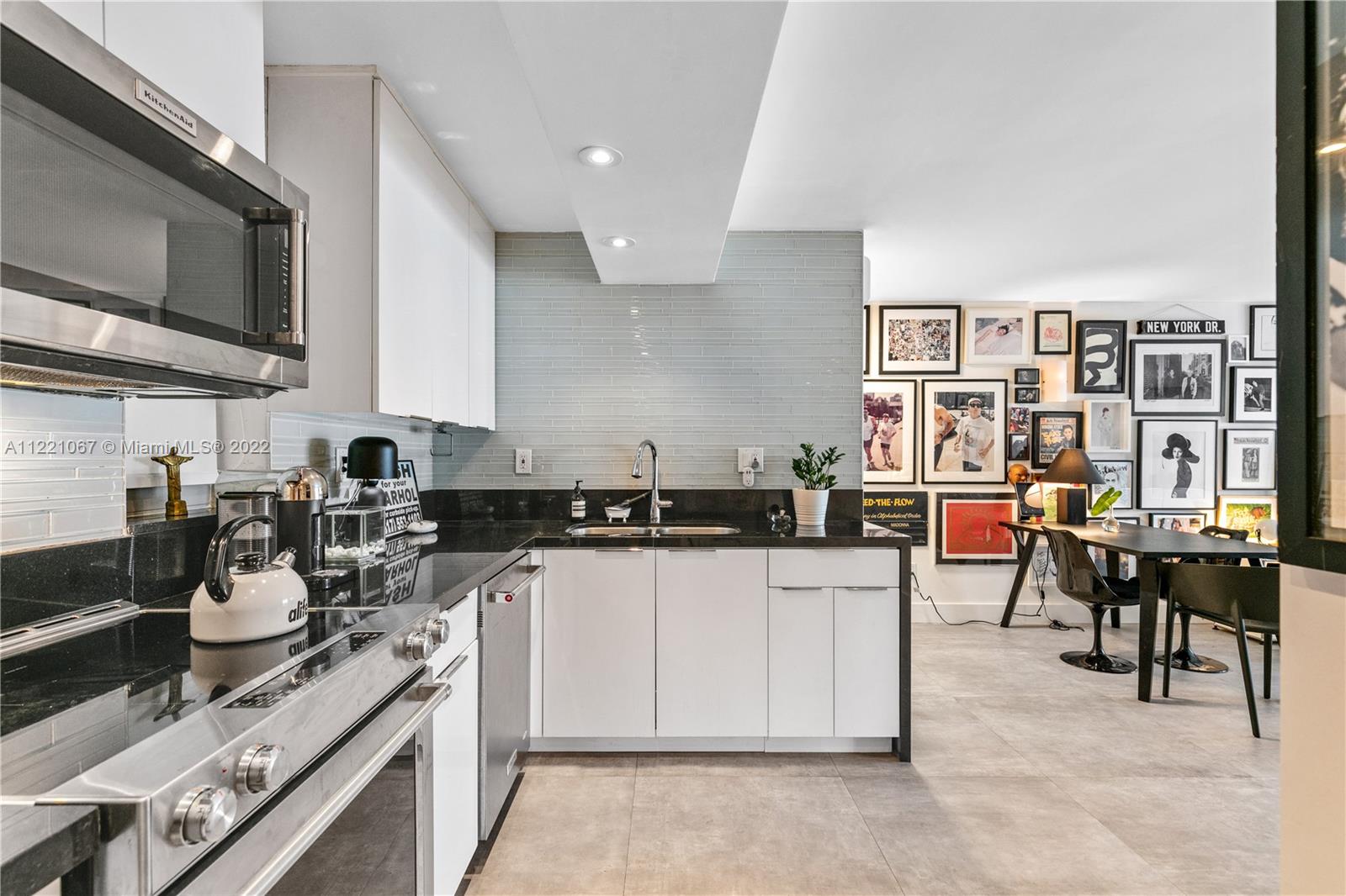 1674 Bay Road, Unit 504 Miami Beach, FL 33139 - Photo 11 of 25 a kitchen with a sink a stove and chairs