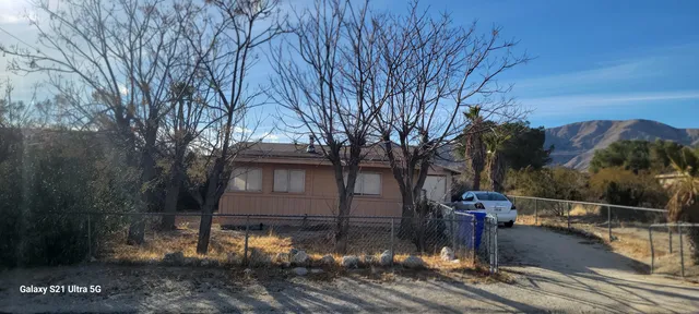 a view of a house with a cars park side of a road
