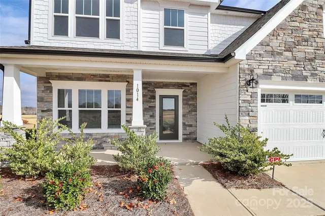 front view of a brick house with potted plants