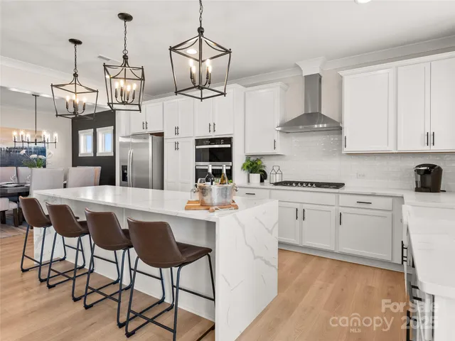 a kitchen with stainless steel appliances granite countertop a kitchen island a stove a table and chairs