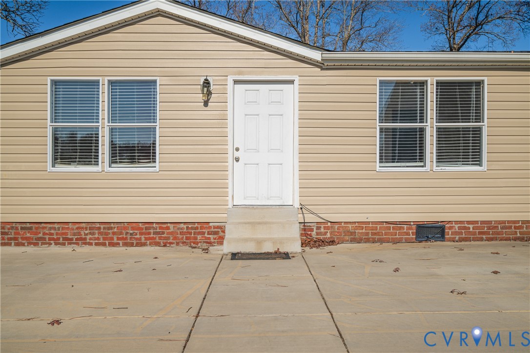 Beige siding exterior with brick foundation and a