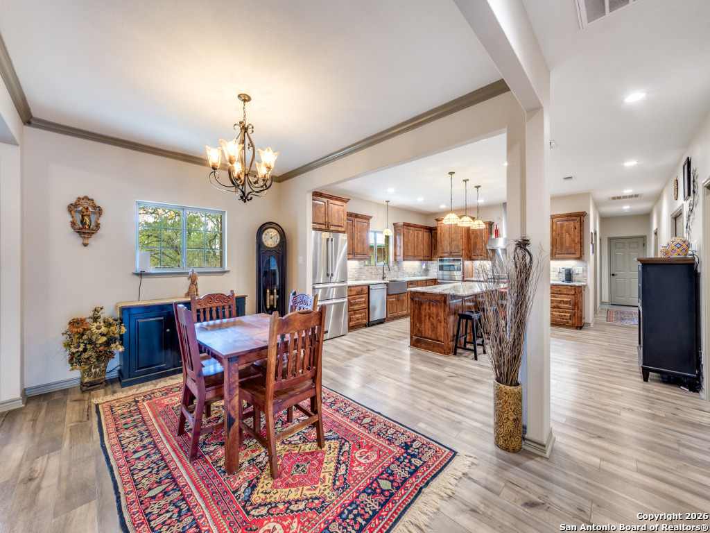 6472 Bluntzer Road Jourdanton, TX 78026 - Photo 5 of 45 a dining room with wooden floor a chandelier a wooden table and chairs