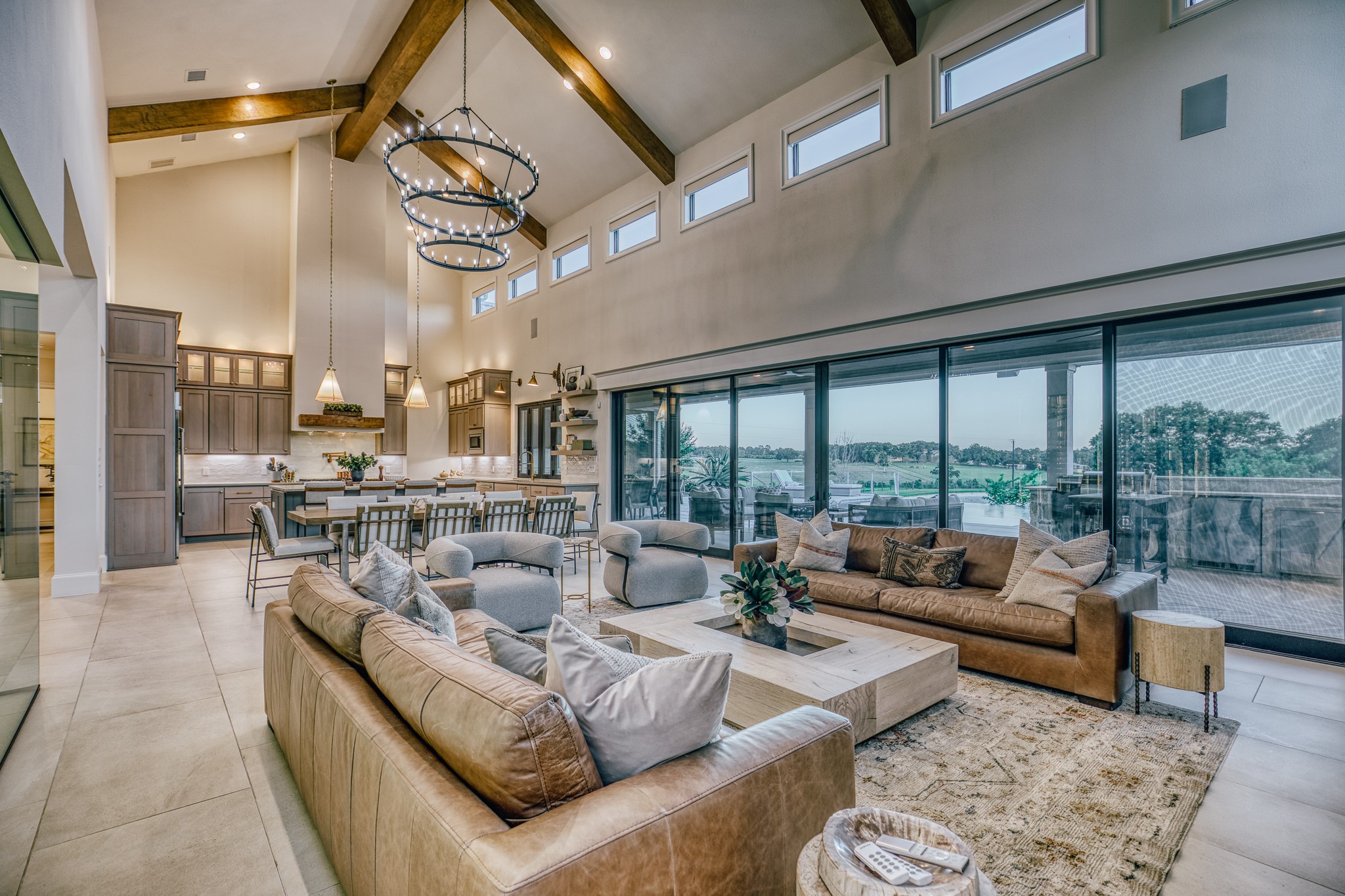 1034 Hilbun Road New Ulm, TX 78950 - Photo 19 of 49 The heart of the home showcases exceptional craftsmanship with vaulted ceilings, exposed beams, a stunning stone fireplace, glass-enclosed wine room, and retractable doors that blur the line between indoor luxury and outdoor living.