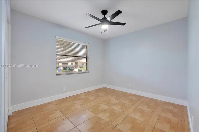 an empty room with ceiling fan and windows