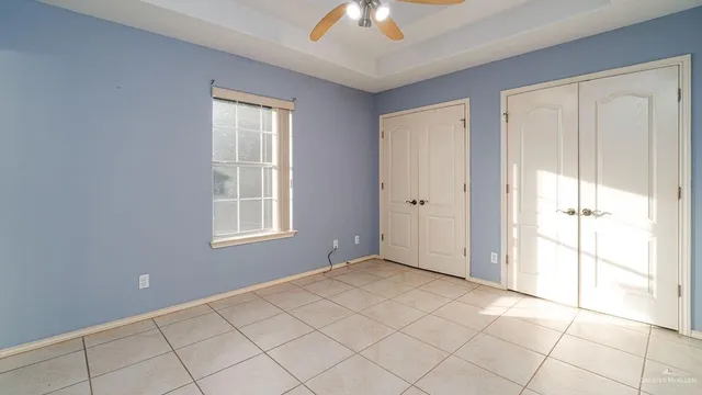 a view of an empty room with window and chandelier fan