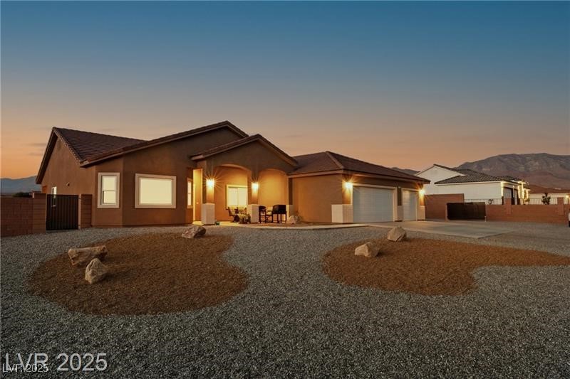 760 Fort Churchill Road Pahrump, NV 89060 - Photo 3 of 33 View of front of home featuring driveway, a garage, stucco siding, and a patio