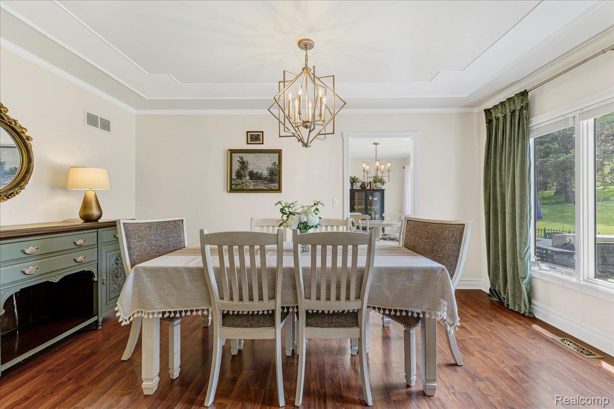 69075 Brookhill Drive Romeo, MI 48065 - Photo 12 of 28 Dining space featuring wood-finish flooring, a coffered ceiling, a contemporary chandelier, and large windows