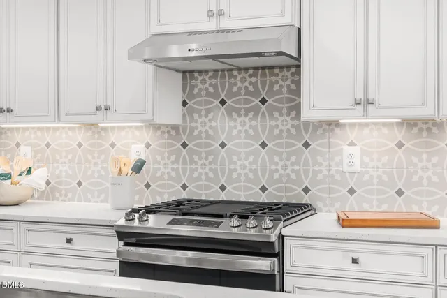 a open kitchen with kitchen island a stove a sink a refrigerator and white cabinets with wooden floor