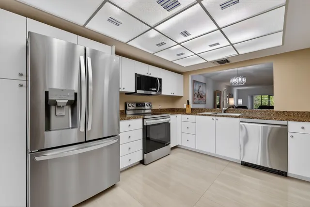 a kitchen with stainless steel appliances granite countertop a refrigerator a stove and a sink with wooden floor