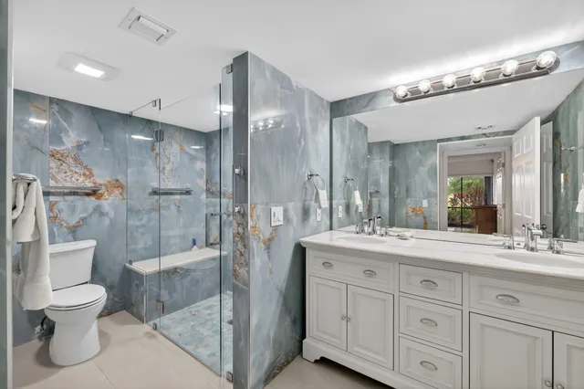 a bathroom with a toilet a sink a light fixture and glass door