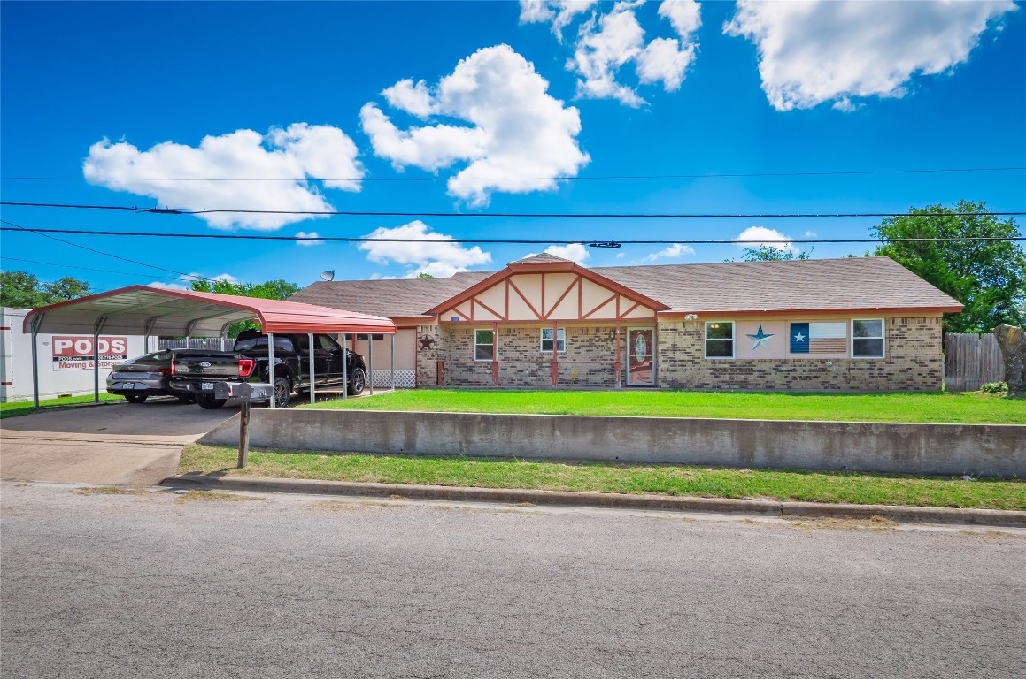 a view of a brick house with a big yard and large trees