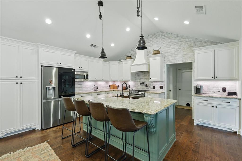 5657 Harmony Ranch Road Aubrey, TX 76227 - Photo 11 of 40 a kitchen with stainless steel appliances kitchen island granite countertop a sink a stove a refrigerator and chairs