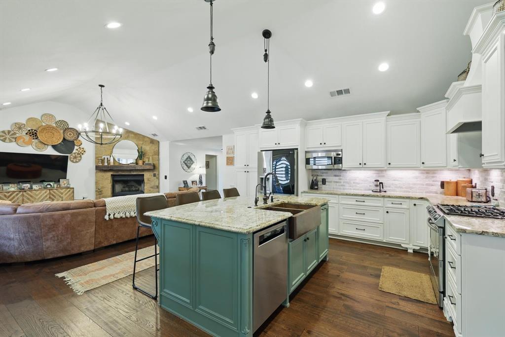 5657 Harmony Ranch Road Aubrey, TX 76227 - Photo 12 of 40 a large kitchen with kitchen island a large island in the center a sink stainless steel appliances and cabinets