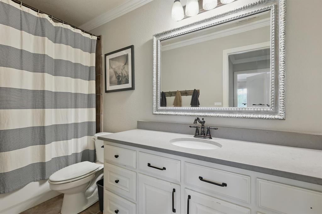 5657 Harmony Ranch Road Aubrey, TX 76227 - Photo 22 of 40 a bathroom with a sink a toilet a mirror and shower curtain