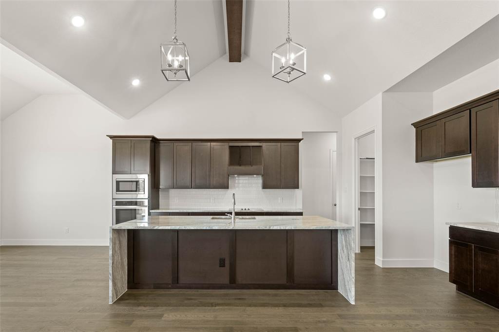 221 Olson Road Waxahachie, TX 75167 - Photo 7 of 24 a kitchen with kitchen island granite countertop stainless steel appliances a sink cabinets and wooden floor