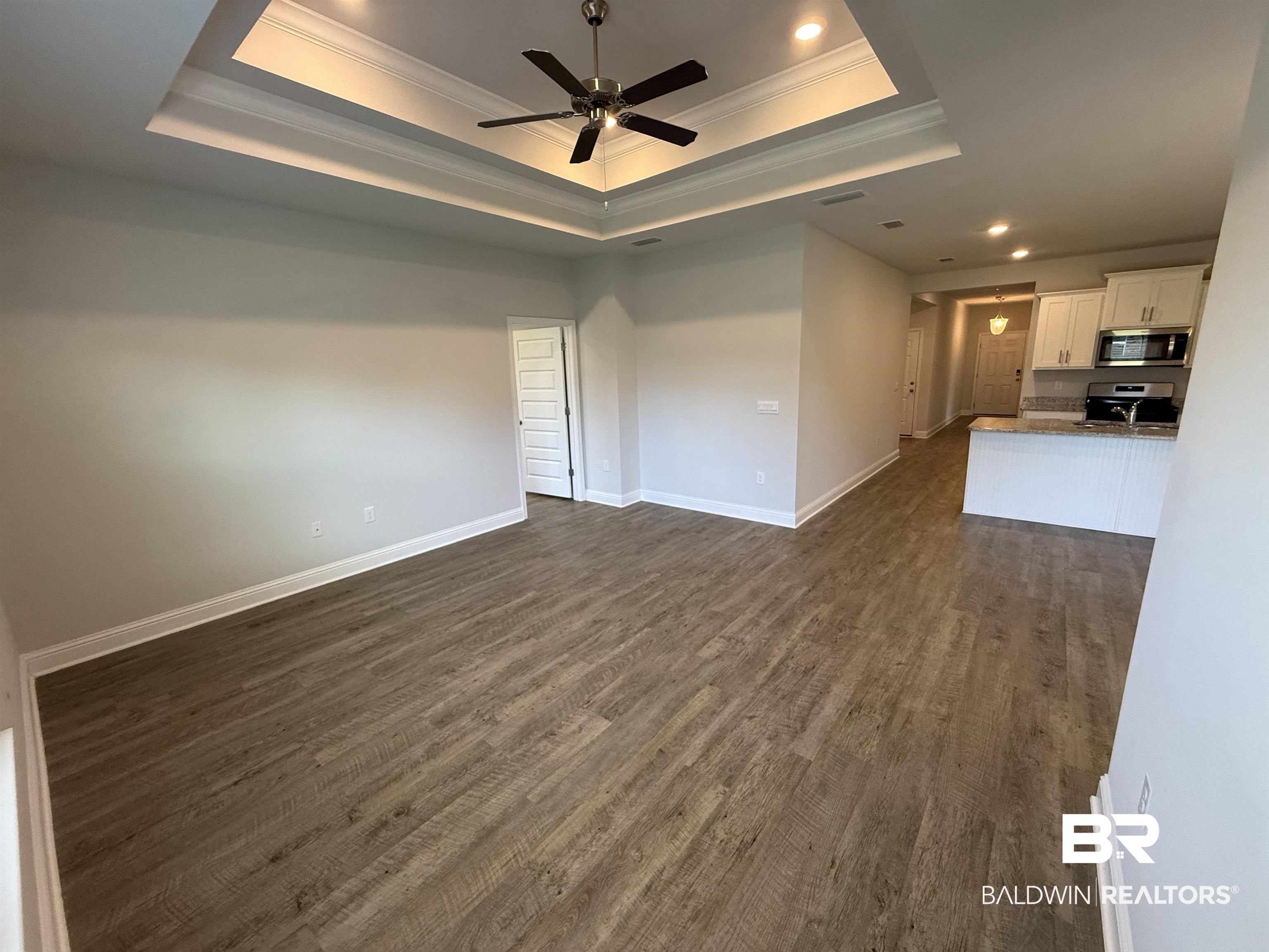 23247 Lieutenant Avenue Foley, AL 36535 - Photo 26 of 47 Open-concept living area featuring wood-finish flooring, a tray ceiling with a ceiling fan, and recessed lighting