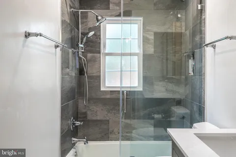 a bathroom with a bathtub shower sink mirror and toilet