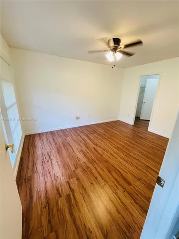 a view of a room with wooden floor a ceiling fan and window