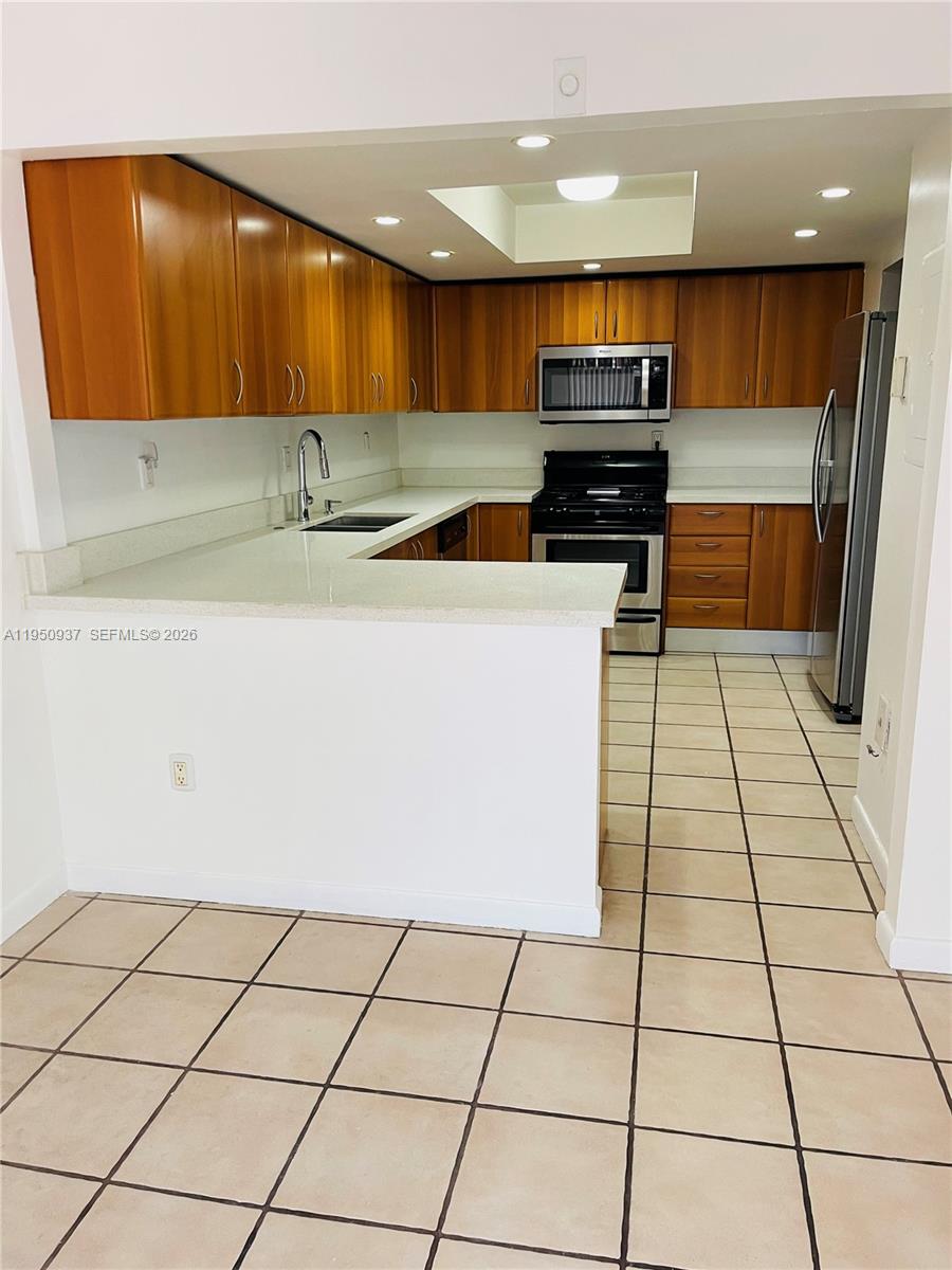 6425 Southwest 116th Place, Unit E Miami, FL 33173 - Photo 6 of 16 a kitchen with granite countertop a stove a sink and a microwave